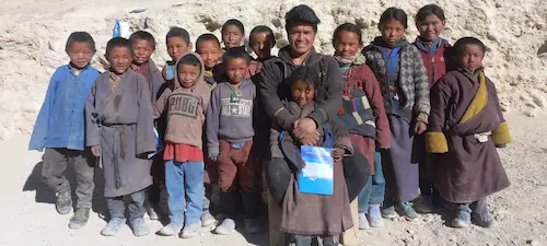 group photo of children with snowman on the back snow falling down.